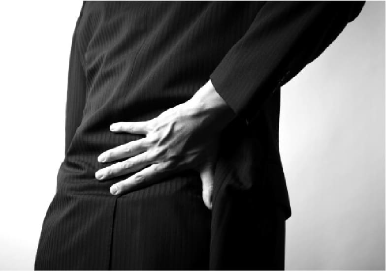 腰椎分離症による腰の痛みに悩み、腰を押さえる様子