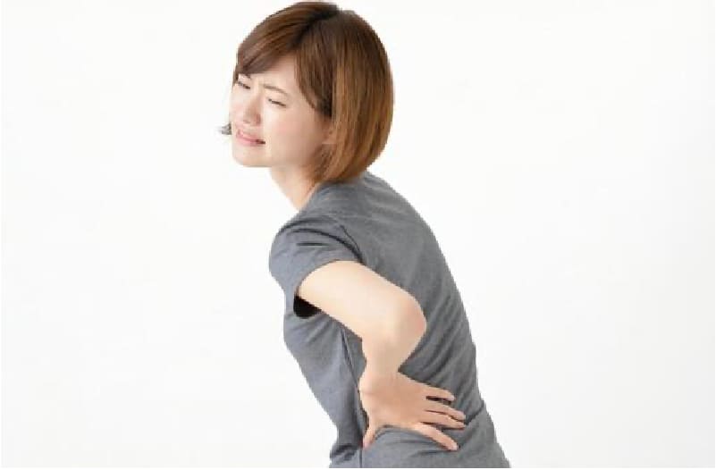 腰痛に悩み腰を押さえる女性